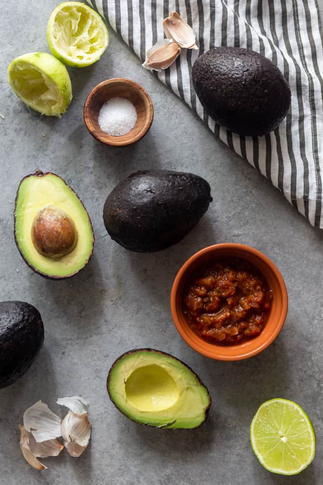 avocados, limes, salt and garlic on a grey surface