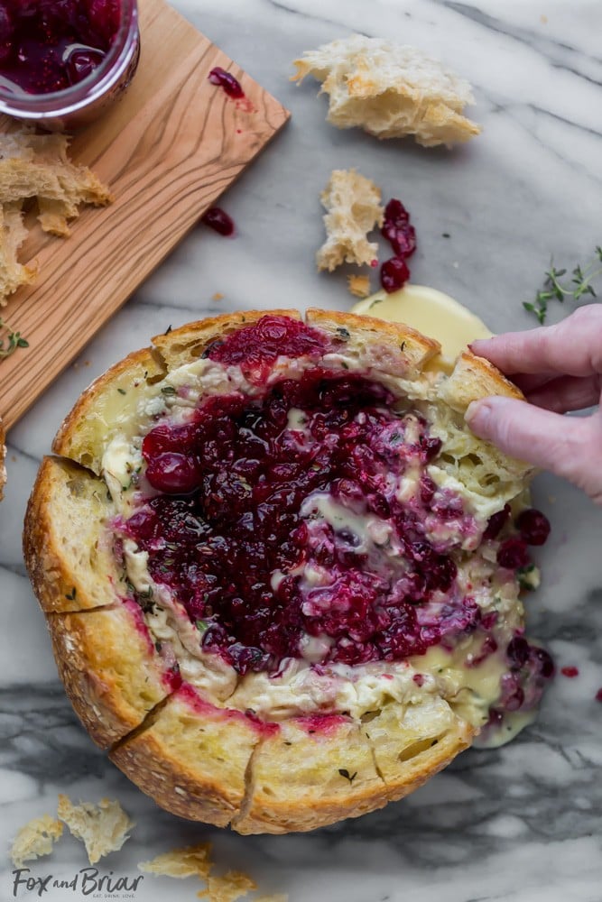 This Tear Apart Baked Cranberry Brie Bread Bowl is a beautiful holiday party appetizer. Melty brie and sweet tart cranberry sauce are a match made in heaven! | Baked Brie | Bloomin' Brie Bread Bowl | Holiday baked brie | Brie and cranberry appetizer | Christmas Appetizer | Thanksgiving Appetizer | New Years Appetizer | Appetizer for parties | Baked Brie Dip in bread 