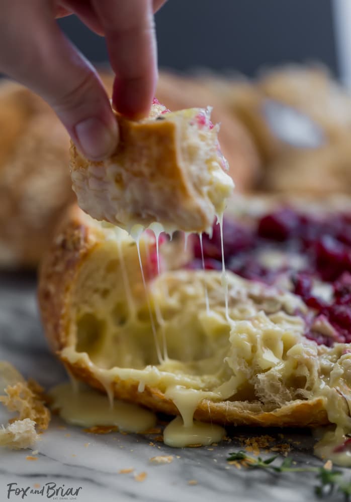This Tear Apart Baked Cranberry Brie Bread Bowl is a beautiful holiday party appetizer. Melty brie and sweet tart cranberry sauce are a match made in heaven! | Baked Brie | Bloomin' Brie Bread Bowl | Holiday baked brie | Brie and cranberry appetizer | Christmas Appetizer | Thanksgiving Appetizer | New Years Appetizer | Appetizer for parties | Baked Brie Dip in bread