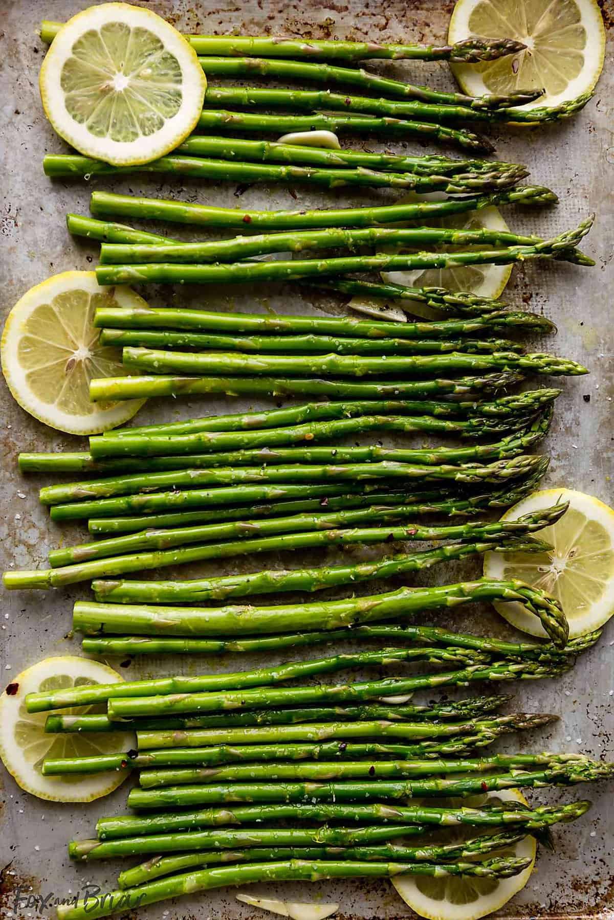 Asparagus spears on a sheet pan with lemon slices