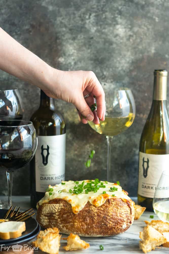 #ad This creamy and cheesy Baked Crab Artichoke Dip in a Bread Bowl will be a hit on game day! A little @darkhorsewine Chardonnay in the dip adds a complex flavor for a winning appetizer. | Dip recipe | party appetizers | crab recipes | Crab artichoke dip | Dip in a bread bowl