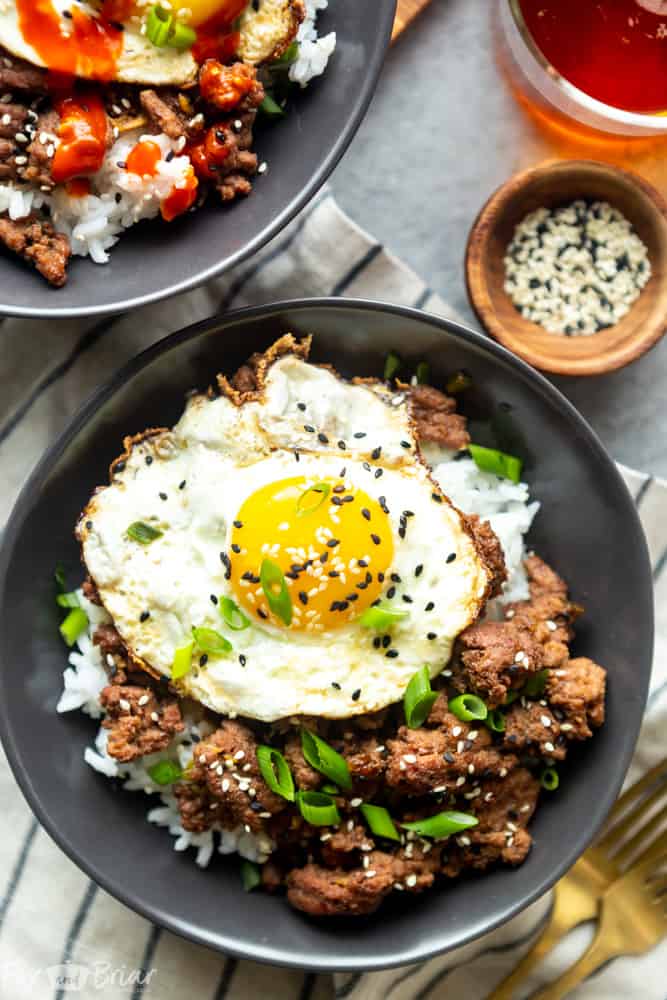 Korean ground beef bowl with a fried egg on top, garnished with black sesame seeds and green onion.