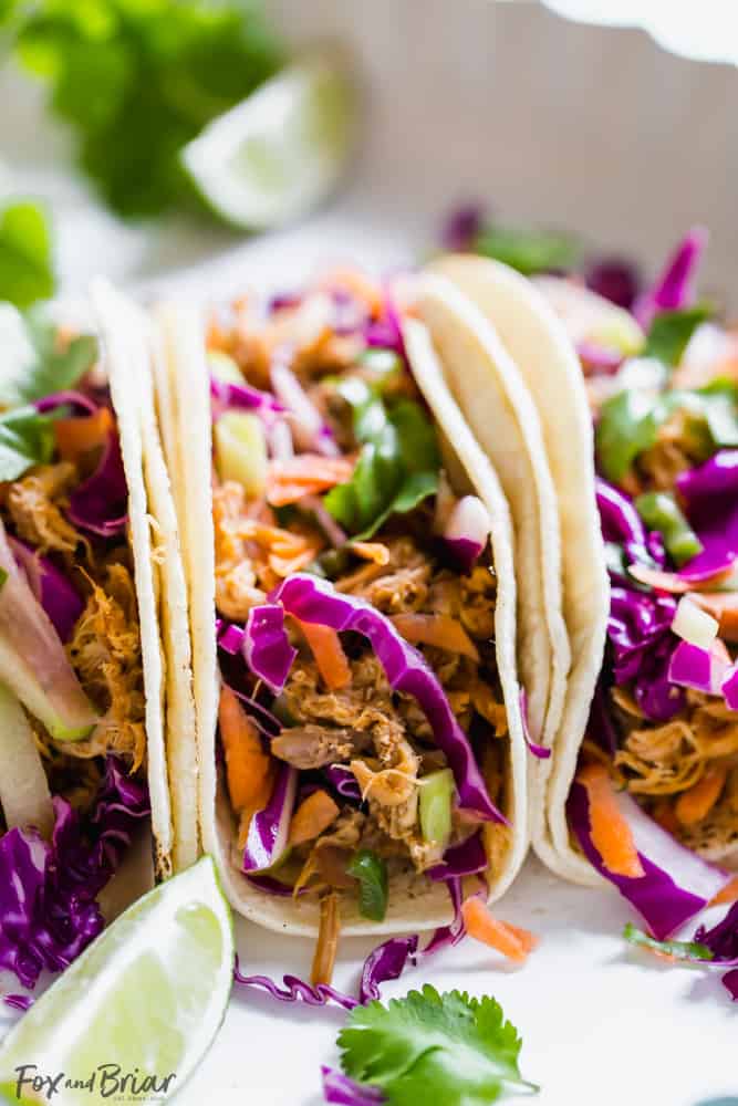 These Slow Cooker Mexican Pulled Pork Tacos have juicy pulled pork, crunchy cilantro lime slaw and creamy avocado crema, all piled in a soft tortilla.  Slow Cooker Pork Tacos | Easy Pork Tacos | Pulled Pork Tacos | How to make pork tacos at home | Shredded pork tacos | Carnitas 