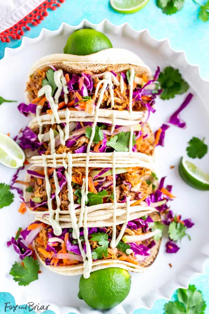 These Slow Cooker Mexican Pulled Pork Tacos have juicy pulled pork, crunchy cilantro lime slaw and creamy avocado crema, all piled in a soft tortilla.  Slow Cooker Pork Tacos | Easy Pork Tacos | Pulled Pork Tacos | How to make pork tacos at home | Shredded pork tacos | Carnitas 