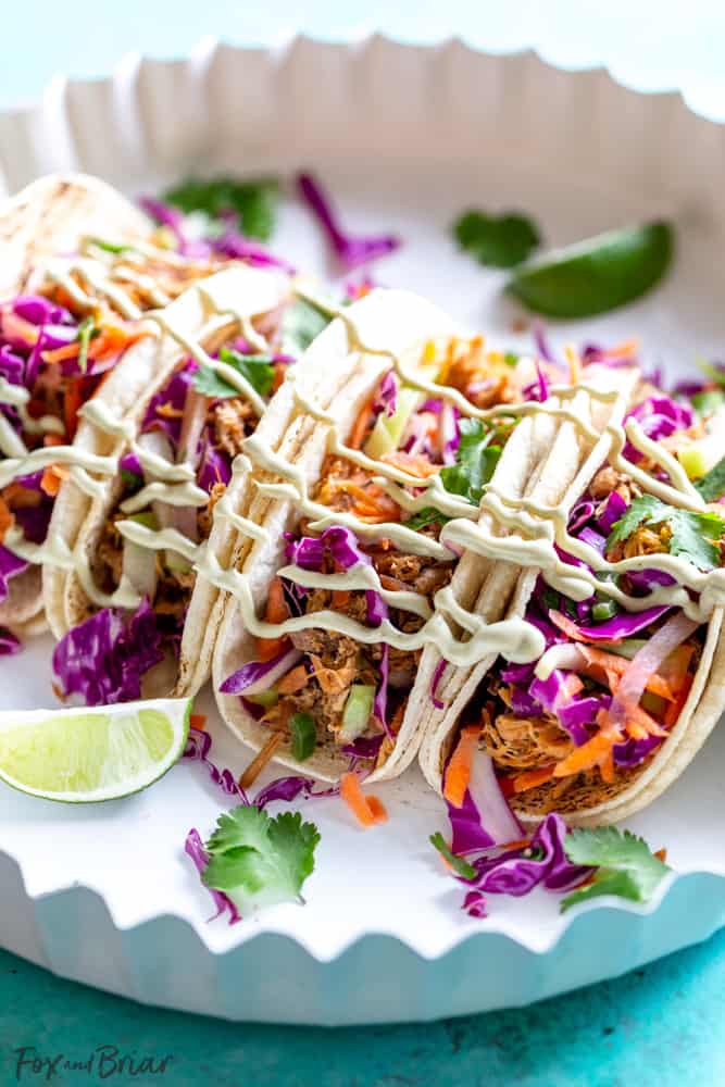 These Slow Cooker Mexican Pulled Pork Tacos have juicy pulled pork, crunchy cilantro lime slaw and creamy avocado crema, all piled in a soft tortilla.  Slow Cooker Pork Tacos | Easy Pork Tacos | Pulled Pork Tacos | How to make pork tacos at home | Shredded pork tacos | Carnitas 