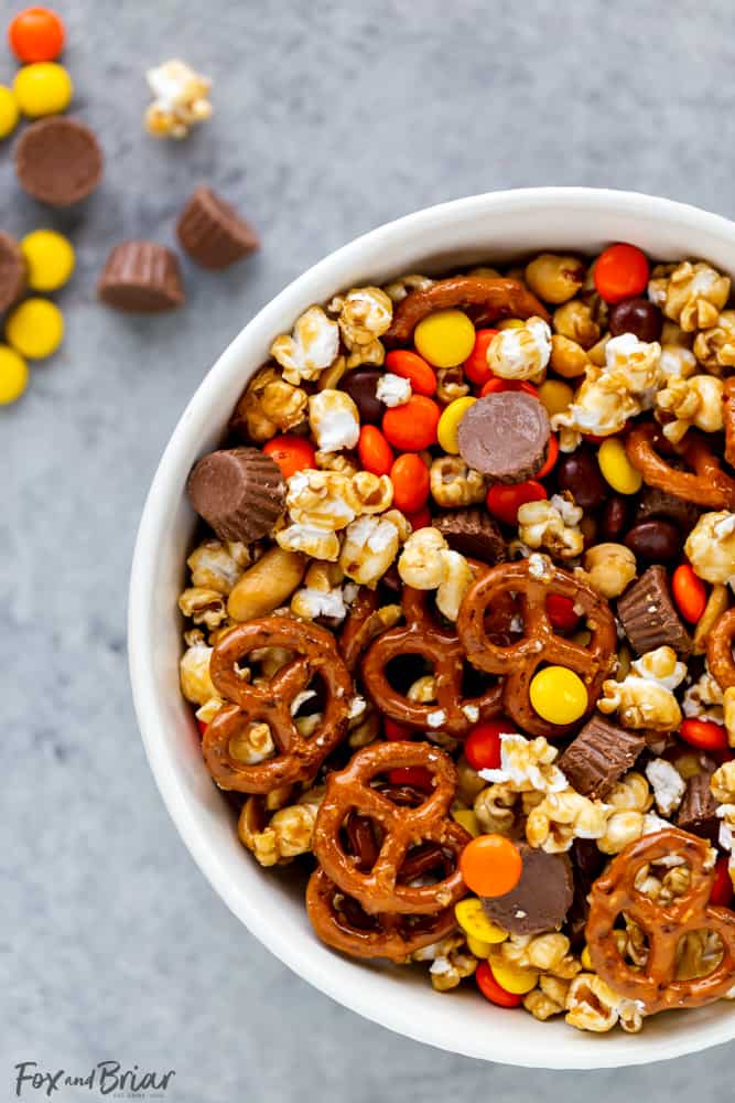 This Chocolate Peanut Butter Sweet and Salty Popcorn Snack Mix is perfect to serve at your next game day party!  Keep them coming back for more with popcorn mixed with Reese's Pieces, Reese’s Peanut Butter Cups Minis , pretzels and peanuts, all mixed together with caramel. #ad @krogerco @reeses | Popcorn recipes | popcorn ideas | sweet poporn recipe | caramel corn | peanut butter chocolate 