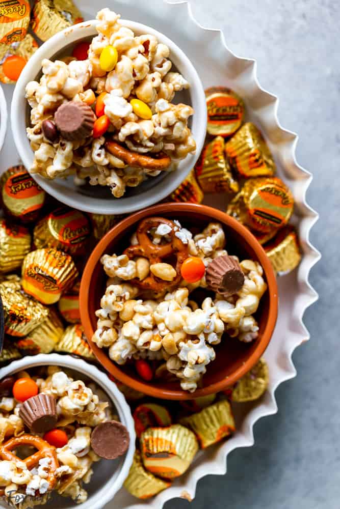 This Chocolate Peanut Butter Sweet and Salty Popcorn Snack Mix is perfect to serve at your next game day party!  Keep them coming back for more with popcorn mixed with Reese's Pieces, Reese’s Peanut Butter Cups Minis , pretzels and peanuts, all mixed together with caramel. #ad @krogerco @reeses | Popcorn recipes | popcorn ideas | sweet poporn recipe | caramel corn | peanut butter chocolate 