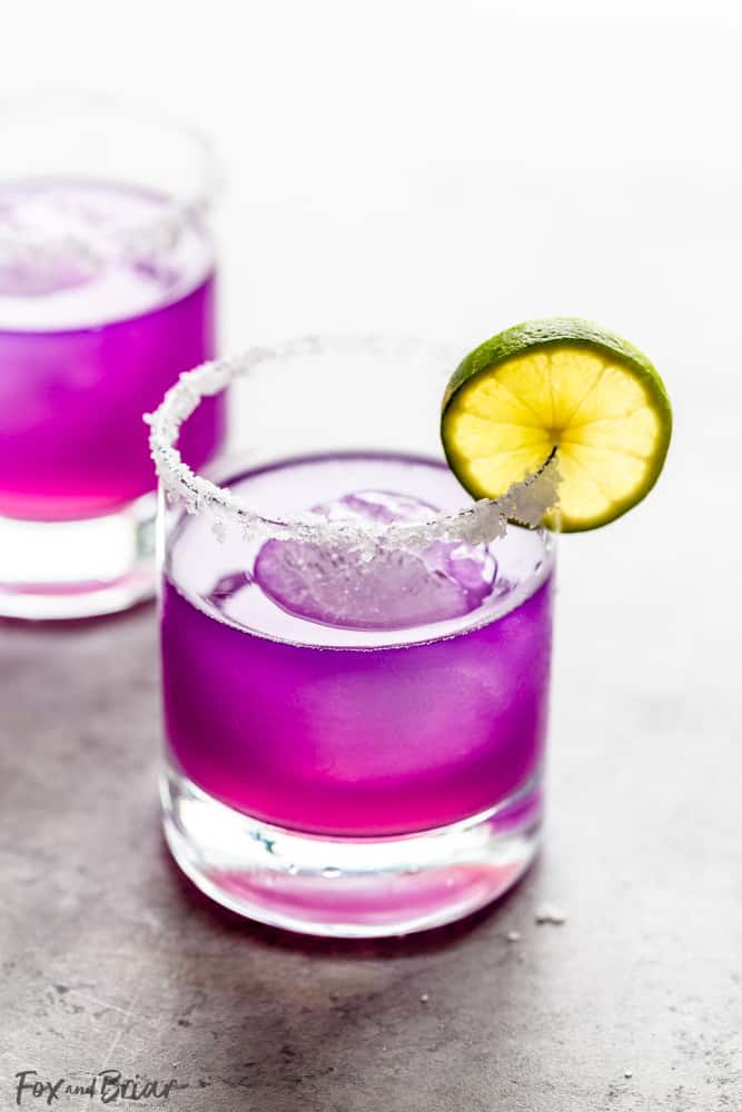 butterfly pea flower margarita with salted rim and slice of lime