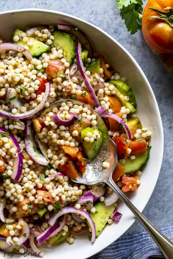 Israeli Couscous salad in a bowl with serving spoon