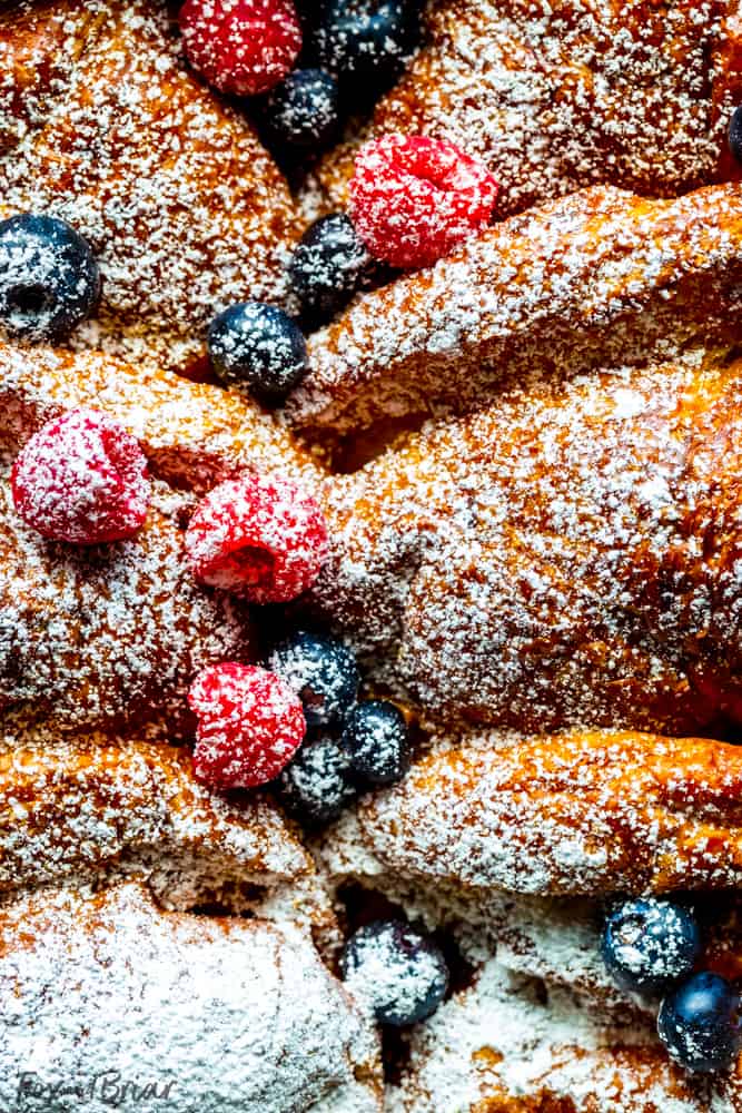 Close up of overnight croissant french toast bake with blueberries and raspberries