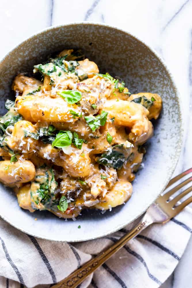 Sausage and gnocchi with a creamy pumpkin sauce in a bowl with Parmesan cheese