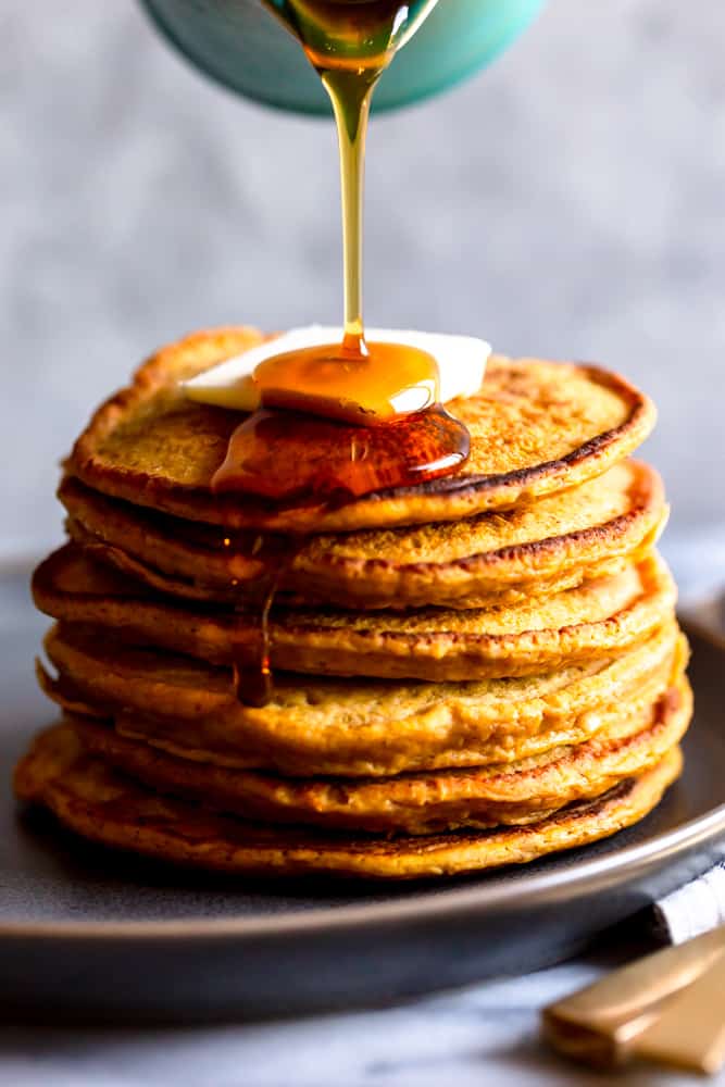 Syrup pouring onto a stack of pumpkin pancakes