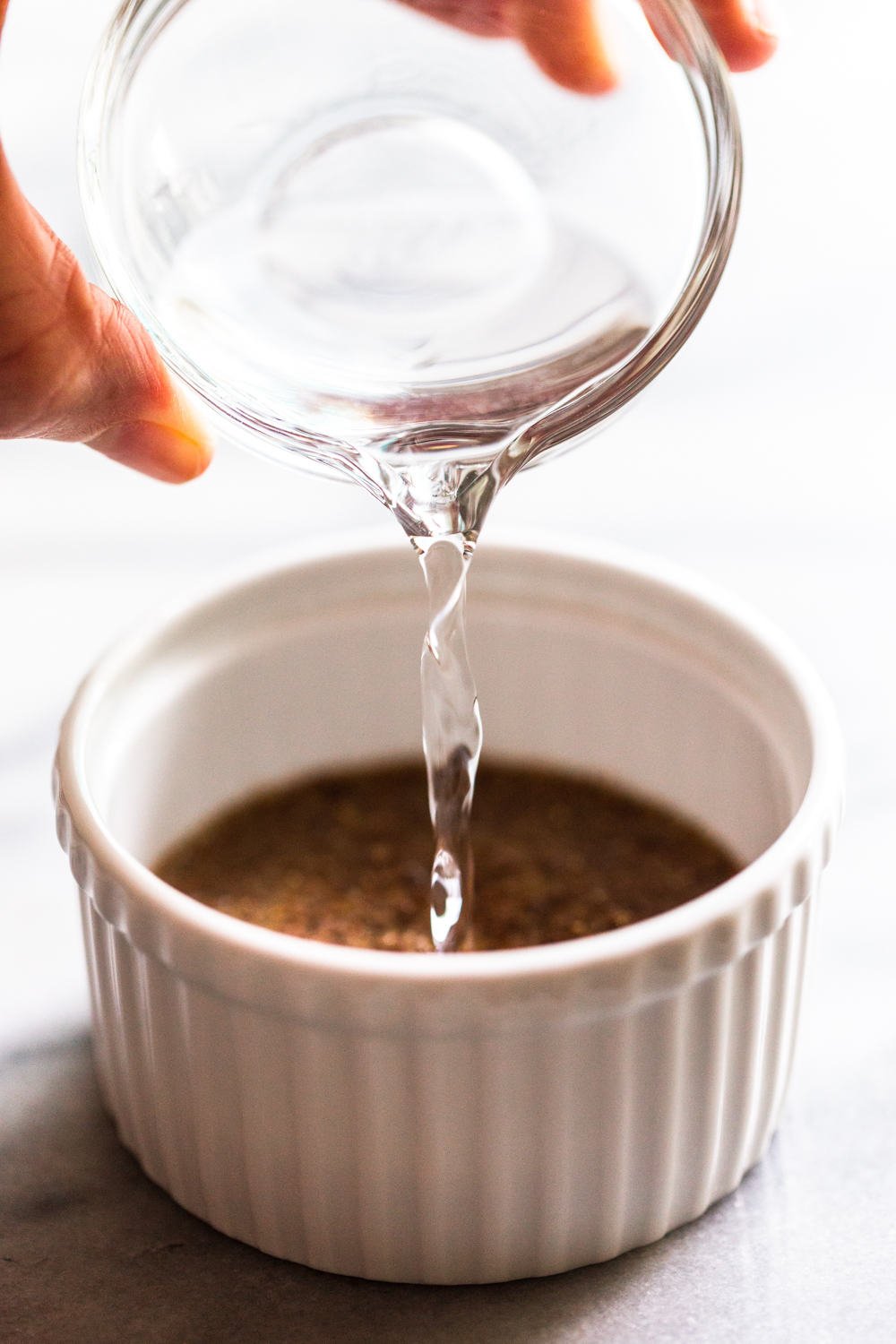 water pouring into a white bowl with ground flax