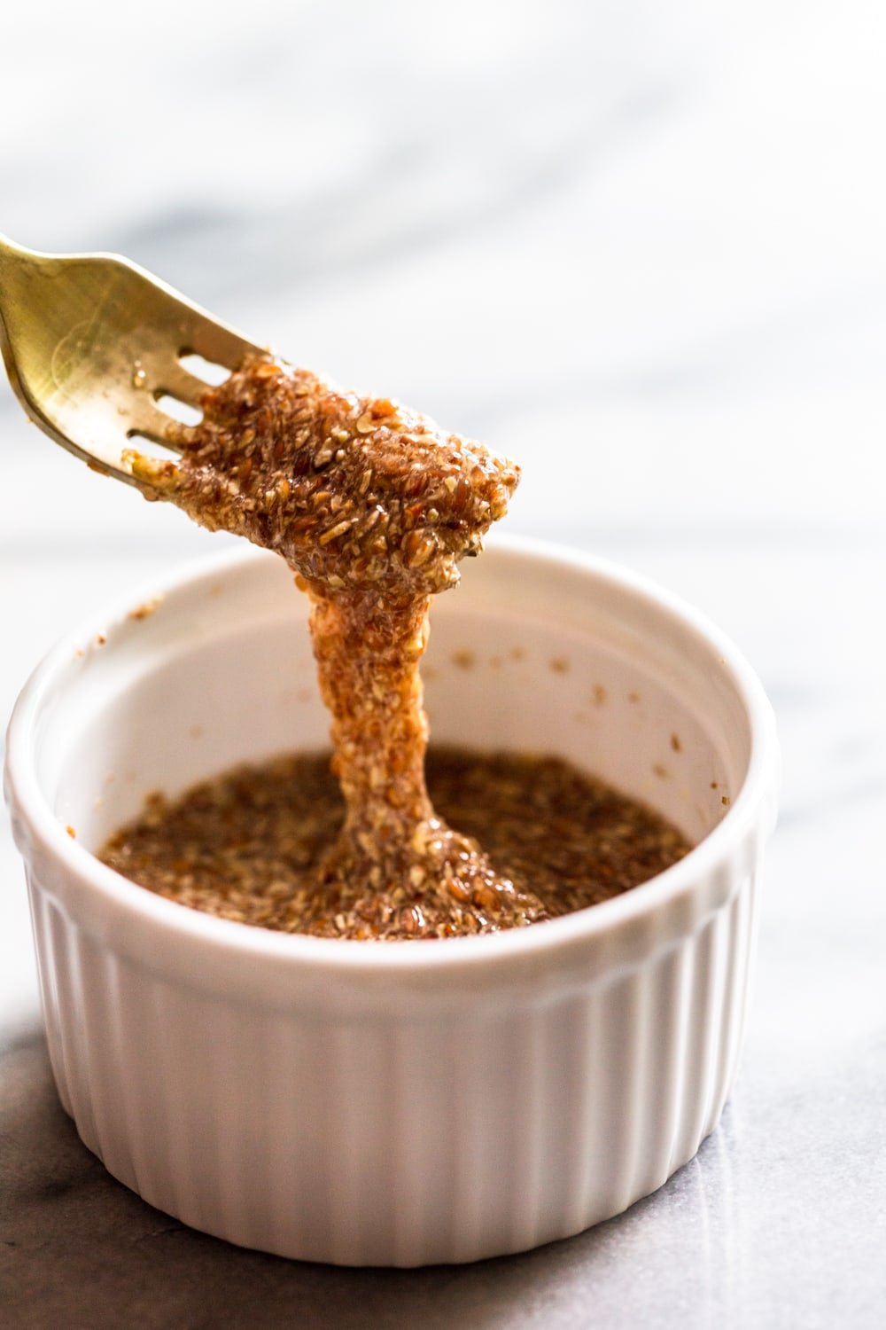 fork dipping into flax egg mixture in a white bowl