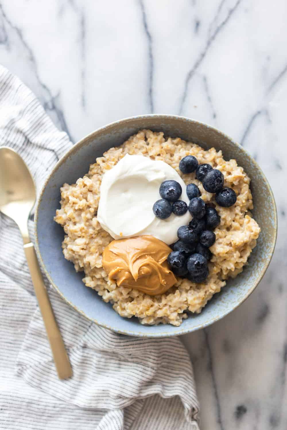 Steel cut oatmeal in a blue bowl on a marble slab