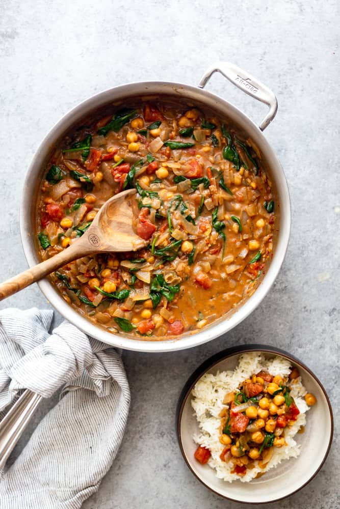 Chickpea Curry in a large saute pan with a wooden spoon