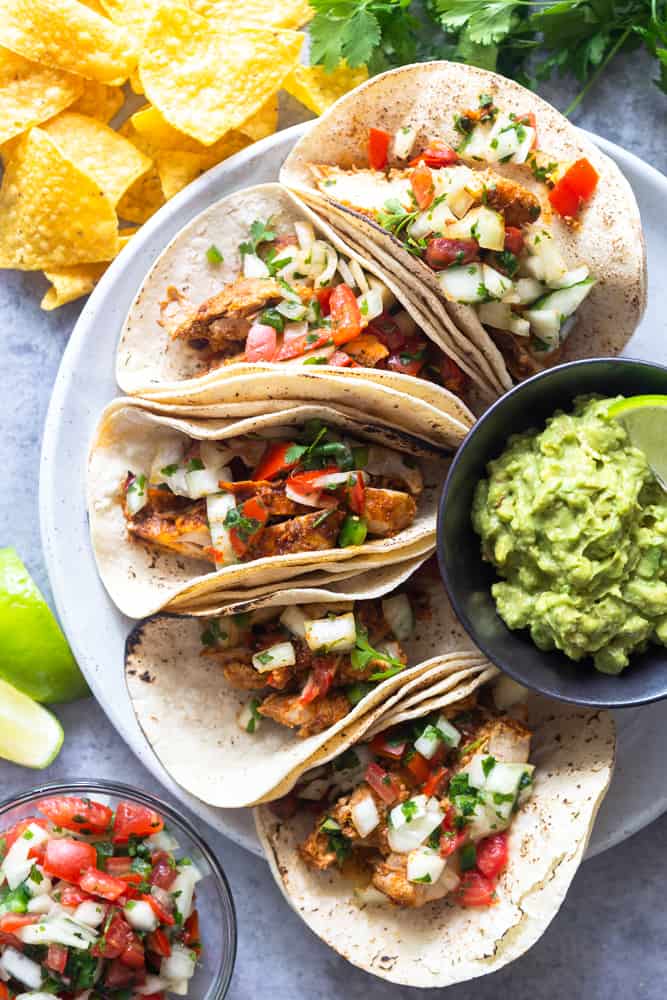 chicli lime chicken tacos on a plate surrounded by tortilla chips and pico de gallo