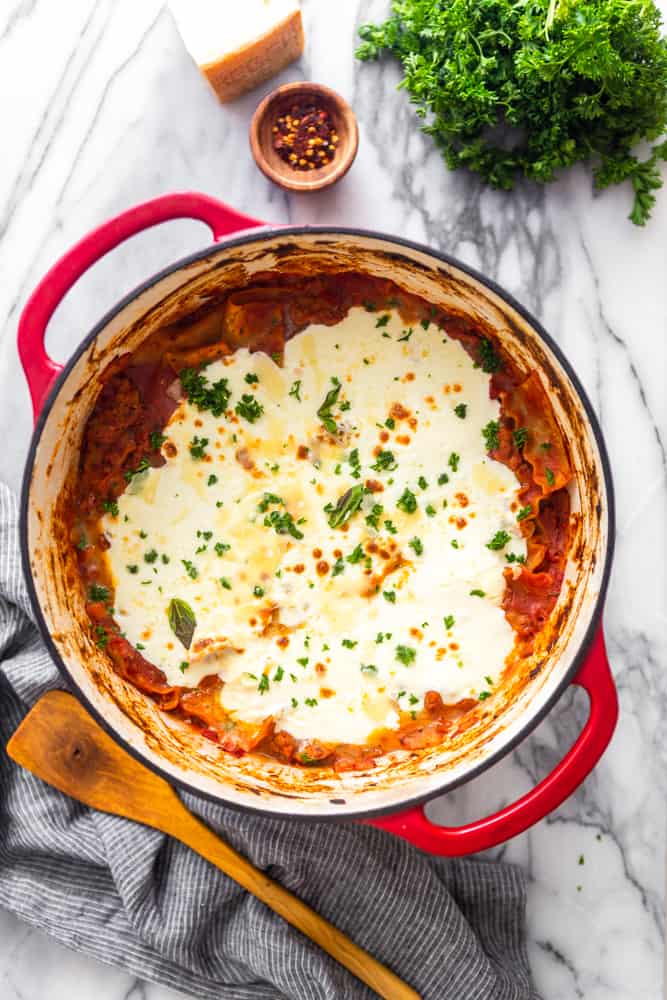 Overhead view of red dutch oven with lasagna and melted mozzarella cheese