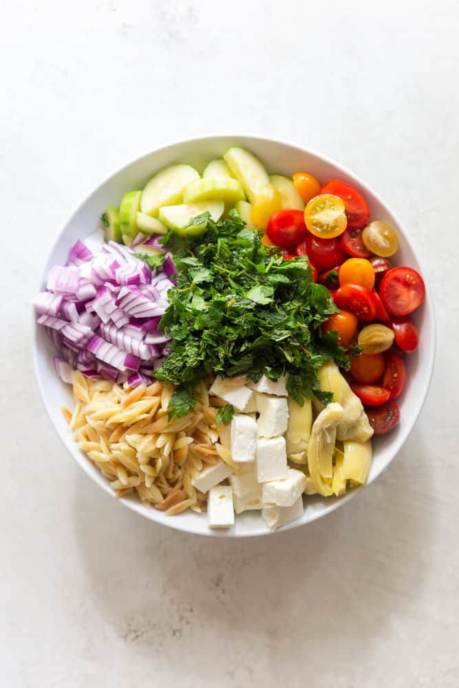 Ingredients for Mediterranean Pasta Salad - orzo, feta, artichoke, tomatoes, cucumbers, onion, herbs