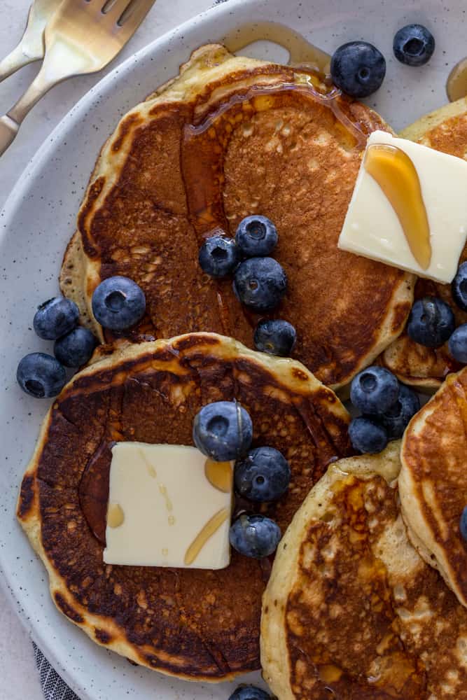 Pancakes on a plate with butter, blueberries and syrup