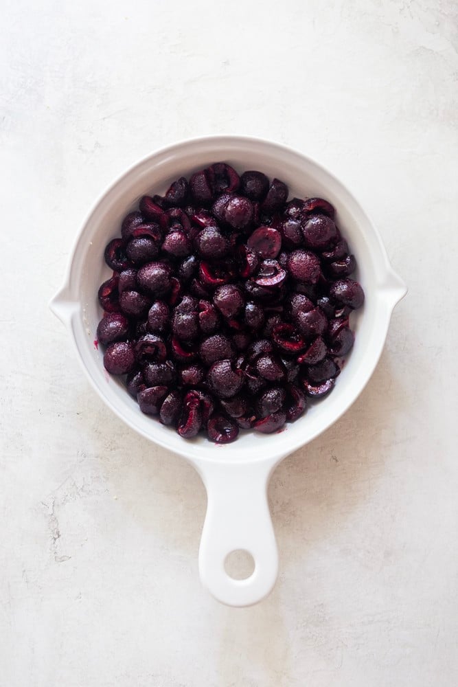 Sliced fresh cherries in a white baking dish