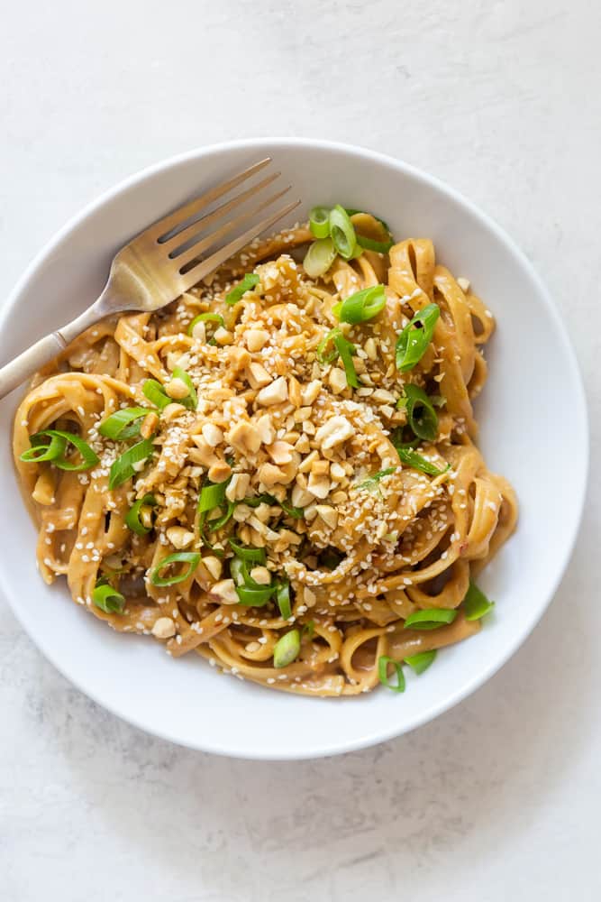 Peanut noodles in a white bowl with a fork