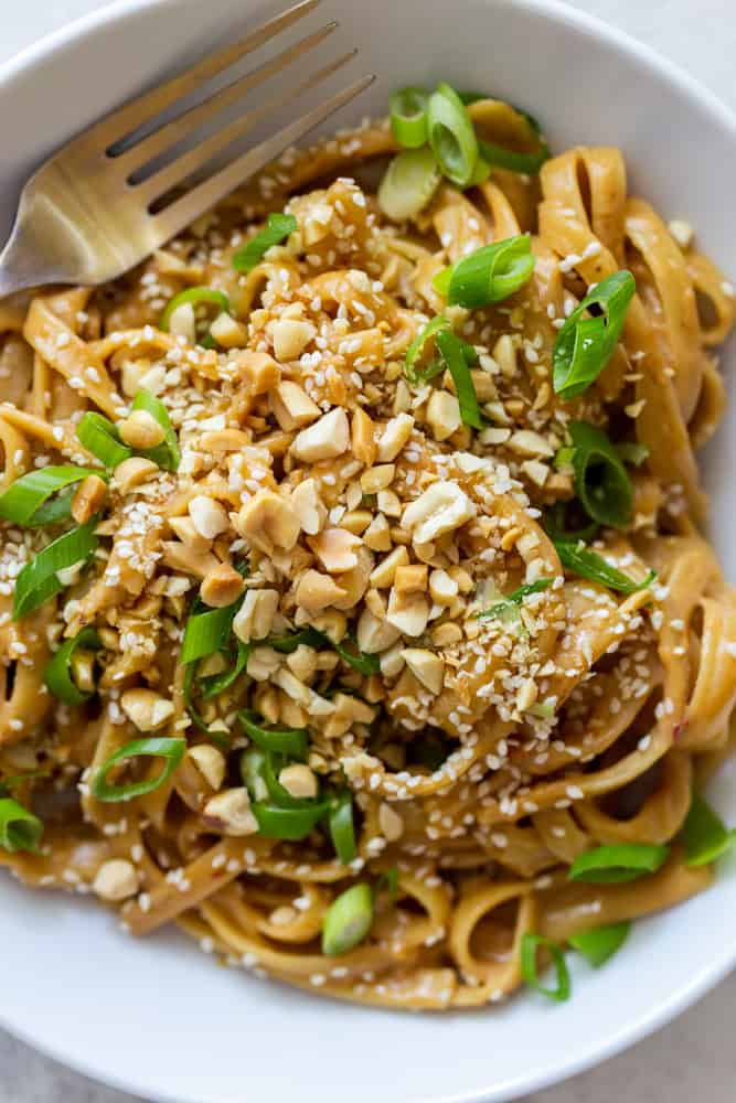 Peanut noodles in a white bowl with a fork