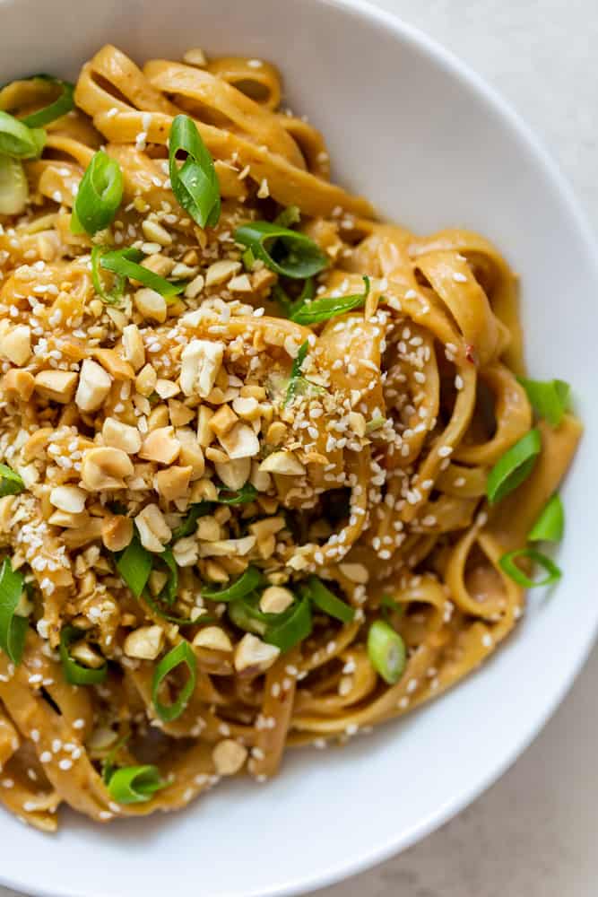 Close up of peanut noodles in a white bowl