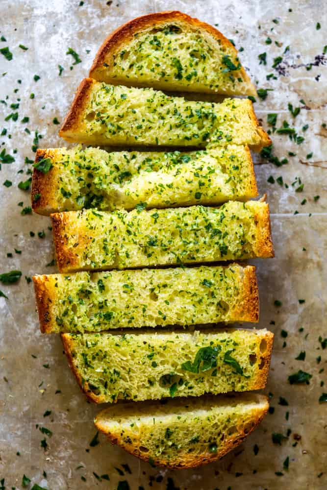 One half of a loaf of garlic bread sliced, on a baking sheet