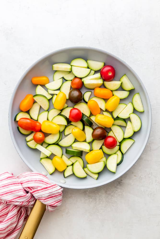 raw zucchini and tomatoes in a pan before cooking