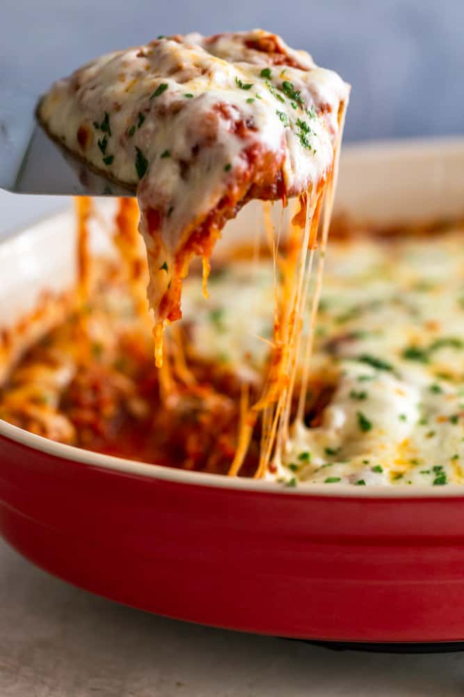 Spaghetti Squash Casserole being lifted out of a dish with a spatula, with cheese stretching from the dish