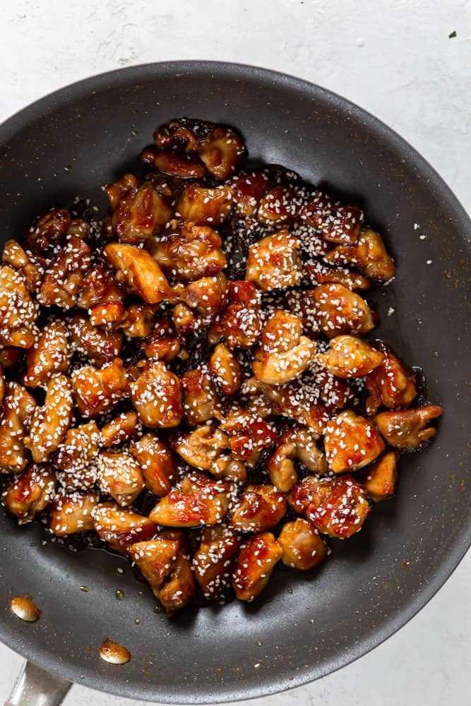 Sesame chicken with sticky sauce and sesame seeds in a pan