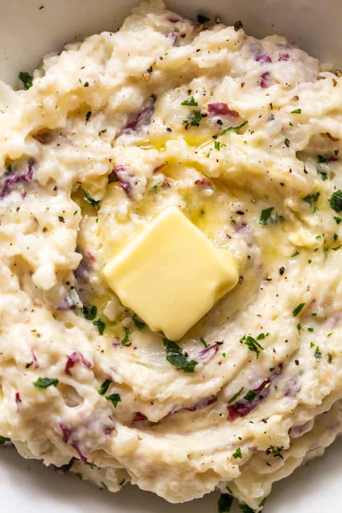 Close up of roasted garlic mashed potatoes with a pat of butter on top. 