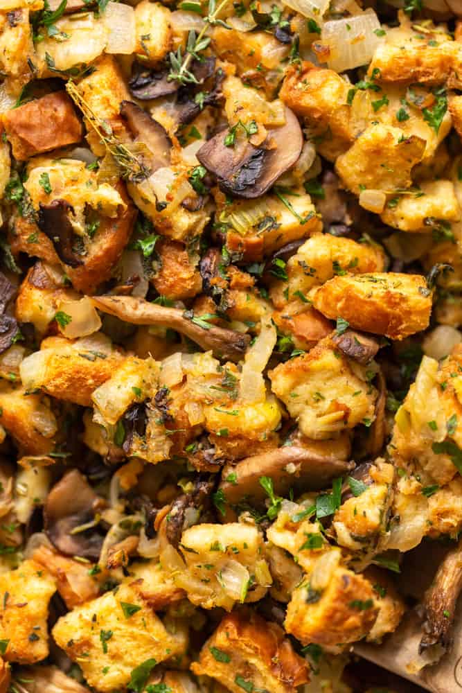 Close up of cooked mushroom stuffing with golden bread, mushrooms and fresh herbs.
