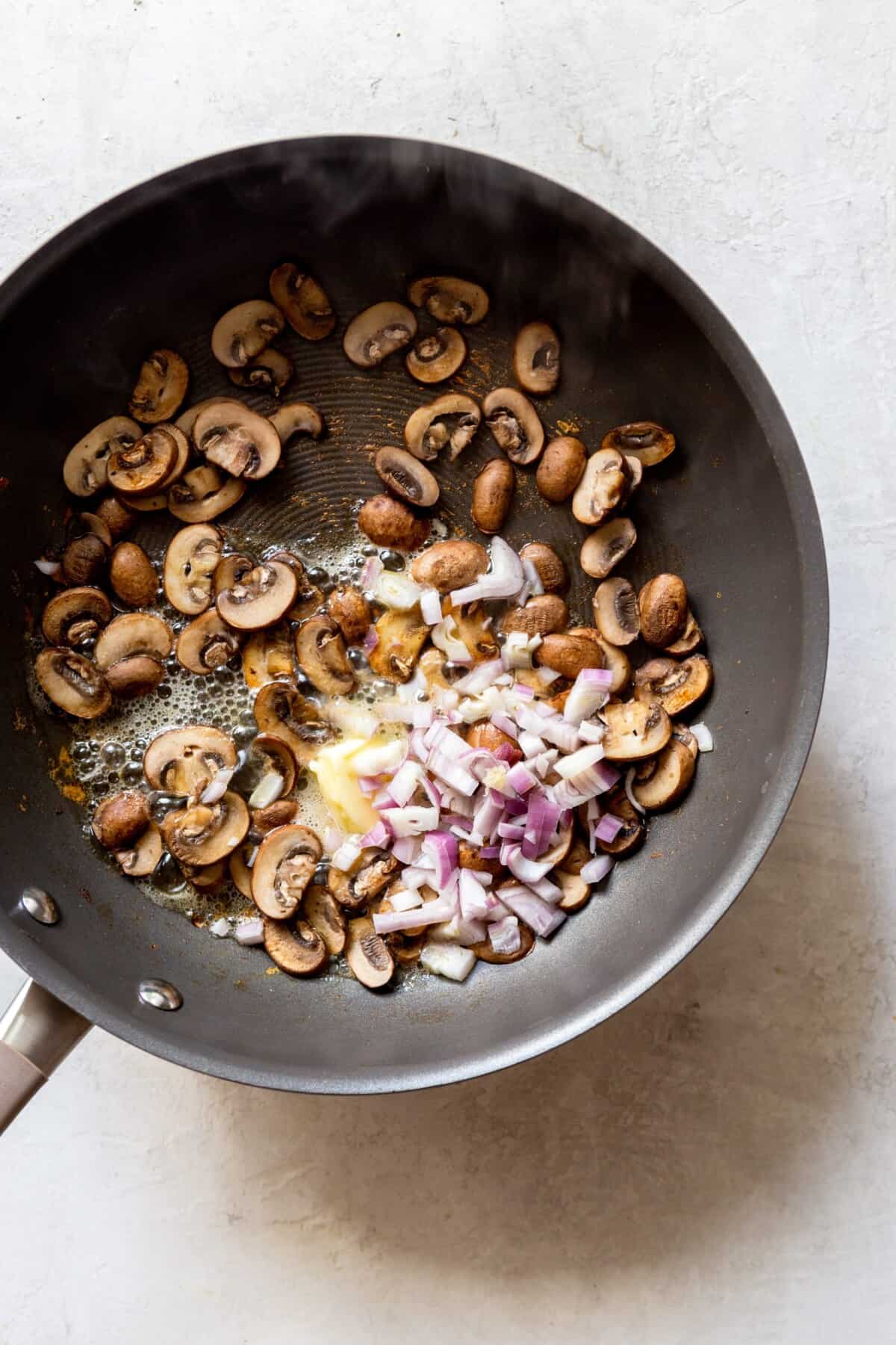 cooked sliced mushrooms with shallots and butter in a pan