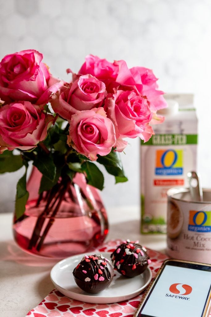 Hot chocolate bombs on a white plate, pink roses in the background