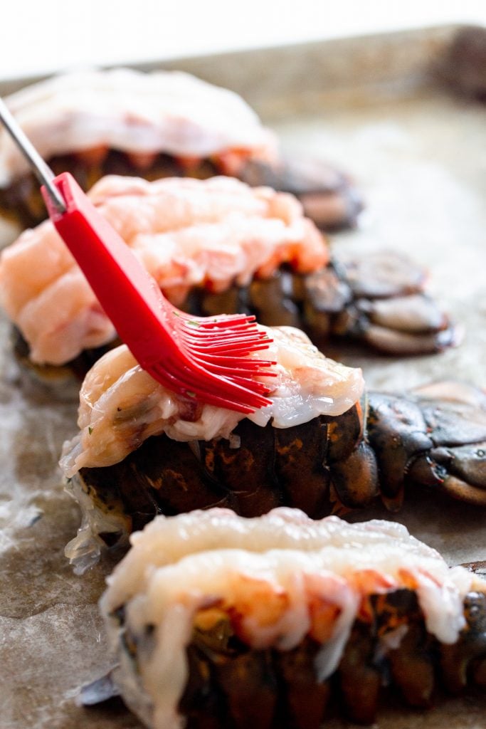 Brushing butter onto a raw lobster tail