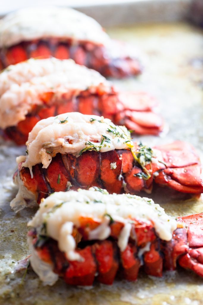 four cooked lobster tails on a baking sheet