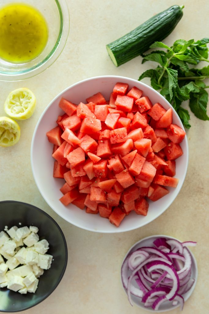 Ingredients for watermelon Feta Salad - cubed watermelon, cucumber, a bunch of mint, cubed feta, sliced red onions, a lemon olive oil dressing. 