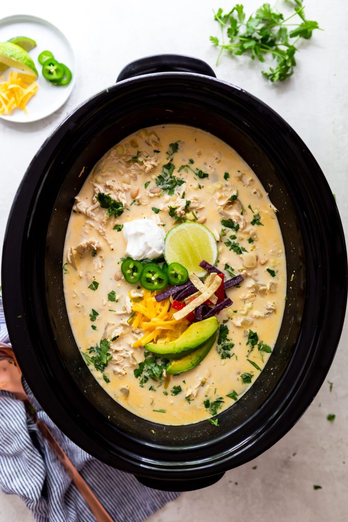 White chicken chili in a crock pot with toppings