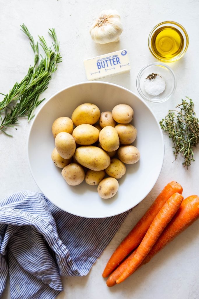 Ingredients for roasted potatoes and carrots - baby gold potatoes, whole carrots, salt, pepper, olive oil, butter, garlic, fresh thyme, fresh roasemary.