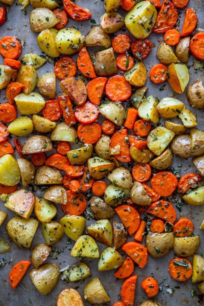Roasted potatoes and carrots with garlic butter and herbs on a sheet pan