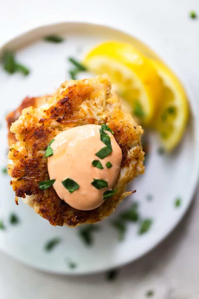 Overhead view of crab cake topped with sriracha aioli.