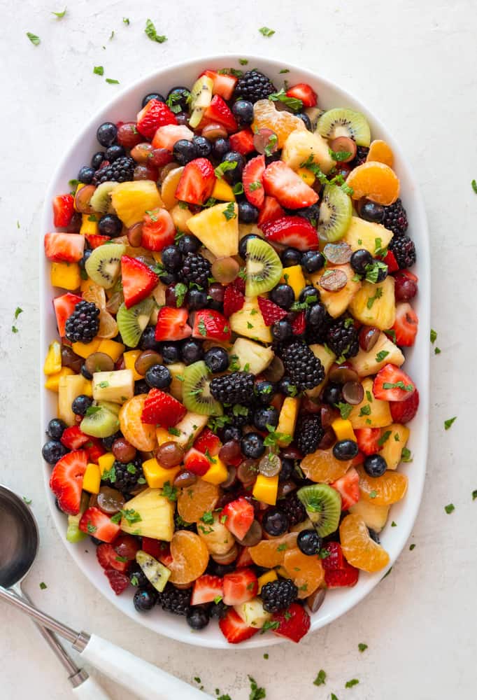 Rainbow Fruit Salad on a white platter, garnished with mint.