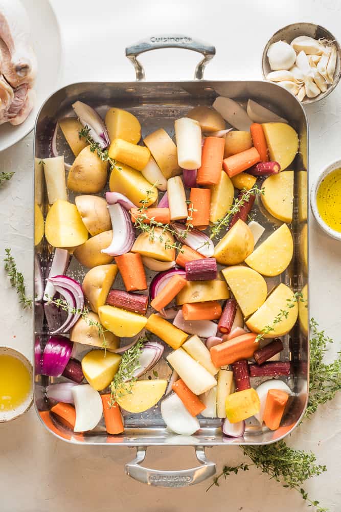 A large roasting pan with potatoes, onions and carrots