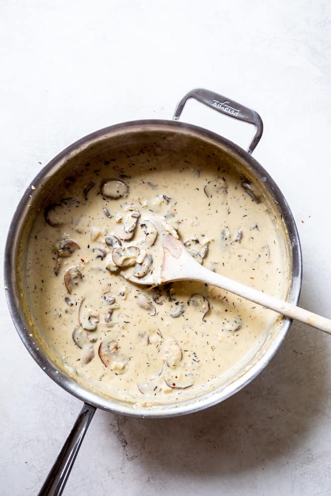 A creamy mushroom sauce in a stainless steel saute pan.
