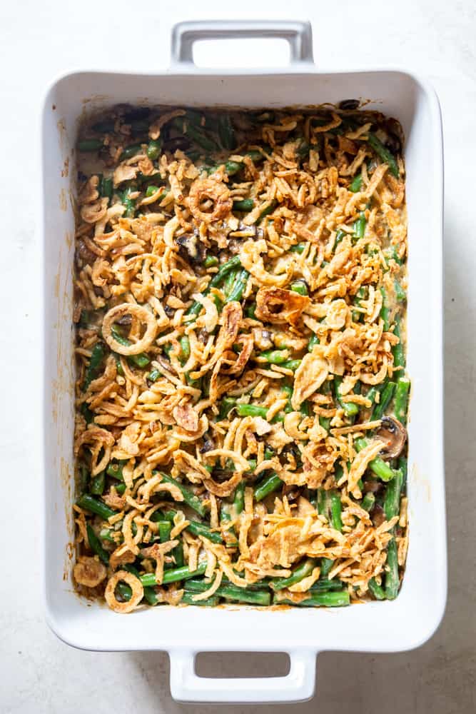 A white casserole dish holding a cooked green bean casserole covered with French fried onions.