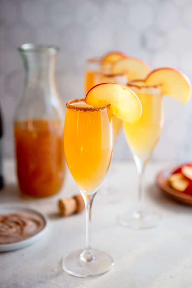 Apple cider mimosas with apple garnish and cinnamon sugar rim.