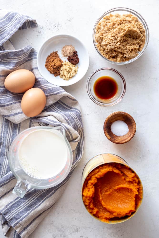 Ingredients for pumpkin pie - brown sugar, spices, eggs, vanilla, salt, half and half, canned pumpkin puree.