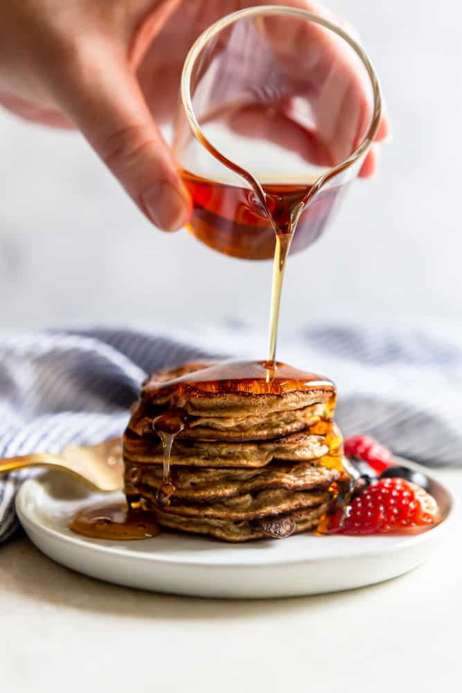 A stack of two ingredient banana pancakes with maple syrup drizzling on top.